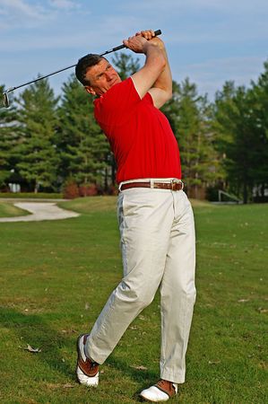 Early season golfer follows the flight of his ball down the fairway.の写真素材
