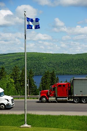 Transport trucks on the Trans Canada Highway with Quebec's flag in the foregroundの写真素材