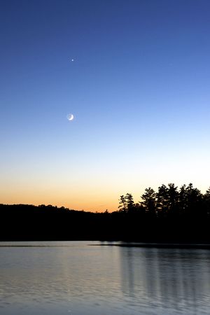 Crescent Moon in sky with trees on the horizon, Canadaの写真素材