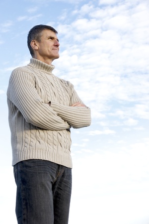 Fifty-year-old standing with hands crossed ponders future plans including his retirement options.の写真素材