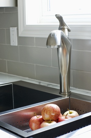 Washing apples is fun in a kitchen renovation featuring 12 inch subway tiles and marbled laminate countertop with a custom sink and faucet.の写真素材