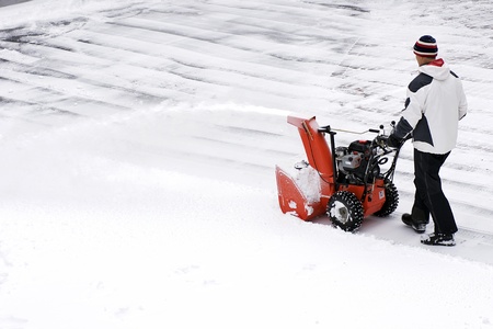 A man clears snow from a driveway with a snow thrower after a winter storm in Canada.の写真素材