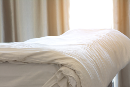 Bedding Sheet on Bed in Bedroom with Sunlight at Morningの写真素材