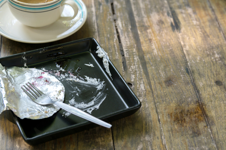 Empty Used Black Plate with Spoon and Coffee Cup on Wood Backgroundの写真素材