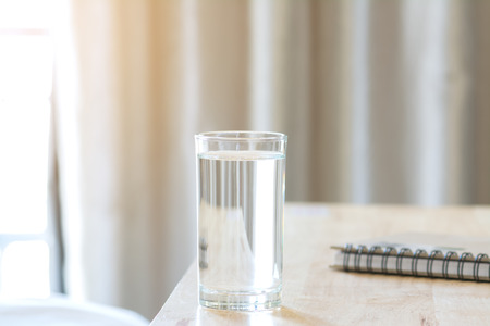 Water Glass on Wood Table with Notebook at Morningの写真素材
