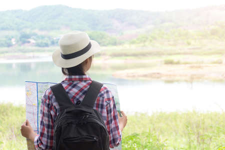 girl traveler with map and backpack in morning at lakeの写真素材