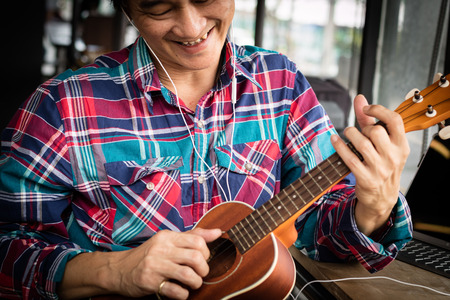 One handsome man was playing a Ukulele enjoyed in the coffee shop.の写真素材