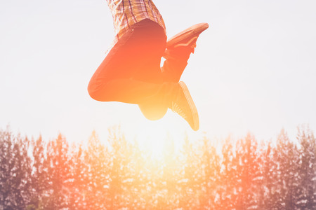 Silhouette of happy people jumping in sunset.の写真素材