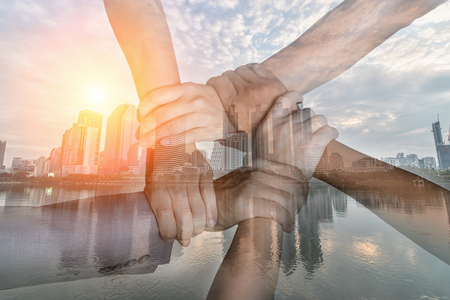 Double exposure of hand  collaboration concept of teamwork and cityscape in sunset