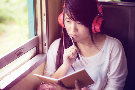 Asian woman listening to music during sitting in a train while traveling.の写真素材