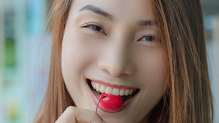Closeup of sexy young beautiful Asian woman with nice lips eating red cherry.の写真素材