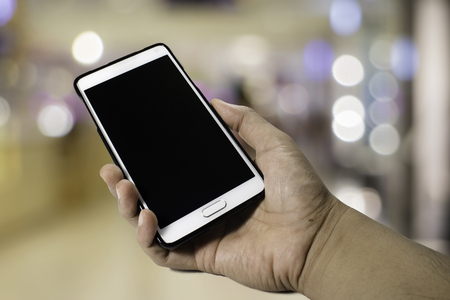 hand hold smartphone on bokeh backgroundの写真素材