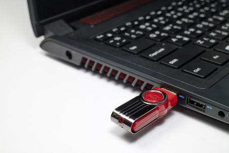 USB flash drive stick connected to laptop computer on white table