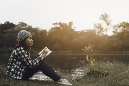 Young hipster woman  sitting in the park with sunset backgroundの写真素材