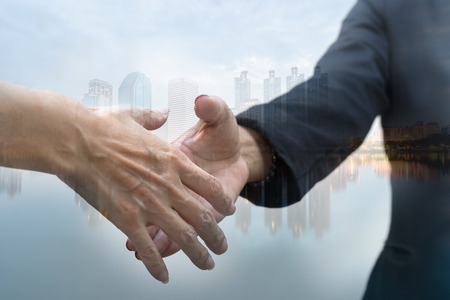 Double exposure of two business people handshake and city with marketing online conceptの写真素材