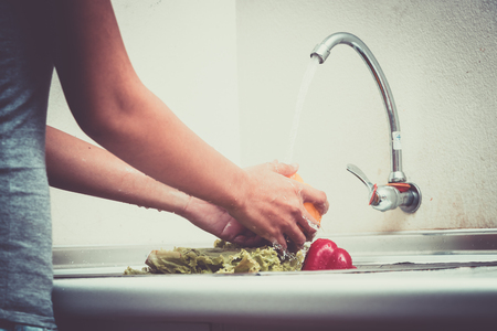 Woman hands are washing vegetables in kitchenの写真素材