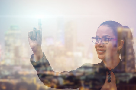 Double exposure of businesswoman are pushing on touch screen and cityの写真素材