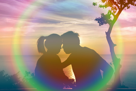 The silhouette of a couple kissing in the sunset.