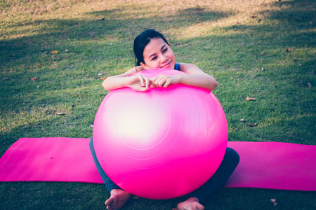Beautiful young women with fit ball doing exercises in the park .の写真素材