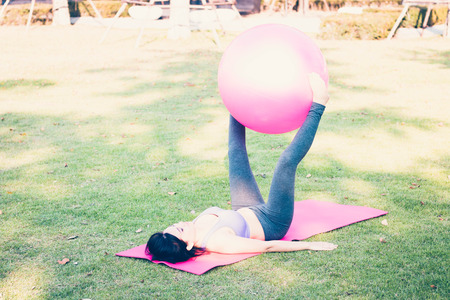 Beautiful young women with fit ball doing exercises in the park .の写真素材