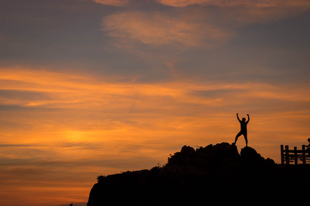 Silhouette of happy people in sunset On the Cliff by the Sea.の写真素材