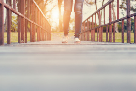 Movement of woman walking on a wooden bridge in the sunset.の写真素材