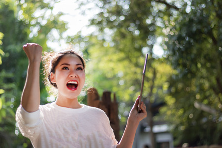Beautiful women have enjoyed in the garden with coffee and tablet.の写真素材
