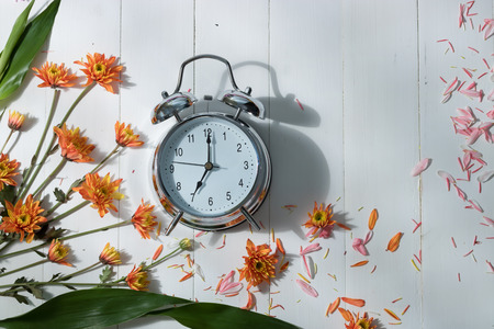 vintage alarm clock on wood and flowers in mornimd lightの写真素材