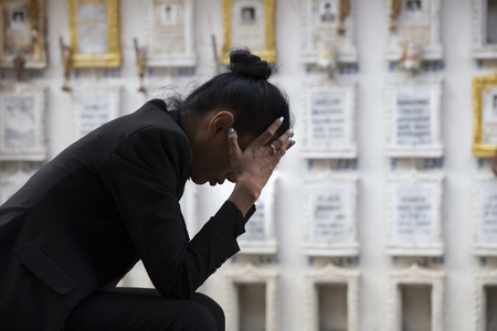 Sad woman sitting near a graveの写真素材