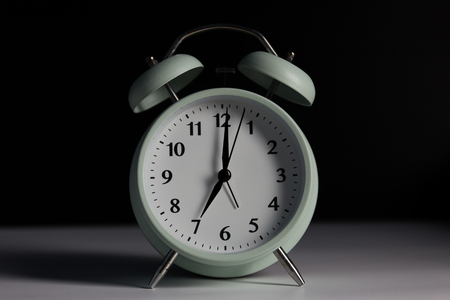 Vintage alarm clock in black background with light.