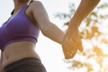Couple walking holding hands in the park the evening.の写真素材