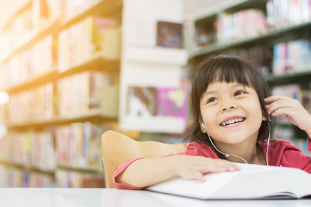 Asian girls are reading books and listening to music in the library happily.の写真素材