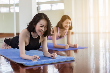 Two young and determined beautifu woman planking in the gym basic plank exercise on mats during workout in a modern fitness の写真素材