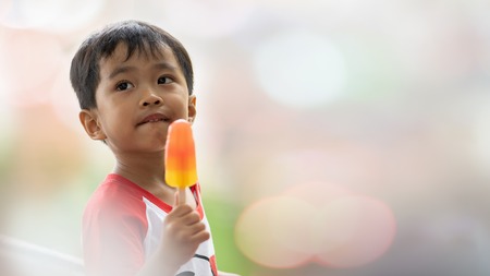 Asian boy eating ice cream in blurred backgroundの写真素材