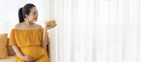 Beautiful Asian pregnant women are enjoying eating fruit and vegetable salads.の写真素材