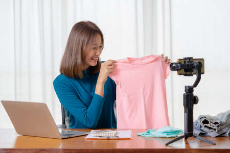 Beautiful Asian girl shop online are broadcasting live products via social media.の写真素材