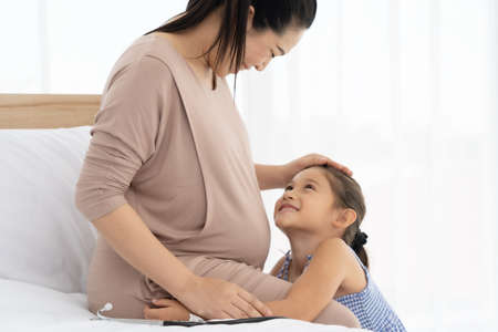 Happy Pregnant women and daughters having fun and  Smiling happily with the fetus.の写真素材