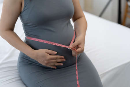 Pregnant women are using a tape measure around the waist.の写真素材