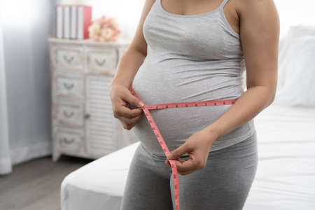 Pregnant women are using a tape measure around the waist.の写真素材