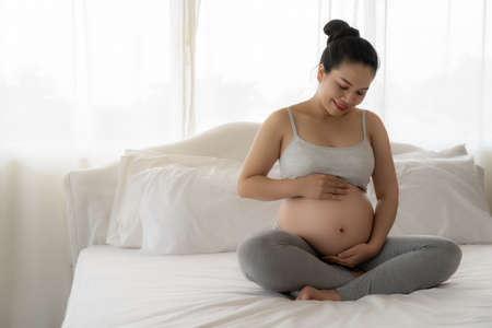 Happy Beautiful Asian pregnant on bedの写真素材