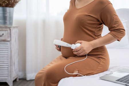 Beautiful Asian pregnant put headset on her belly for baby songの写真素材