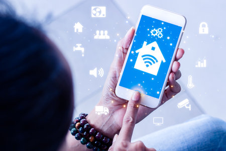 Woman hands using smart phone for mobile phone with smart home app in modern living roomの写真素材
