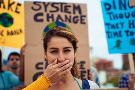People with signs demanding "climate change" Justice and Climate. Group of demonstrators fight for climate change. Symbol of woman silenced by politics? Imageの写真素材