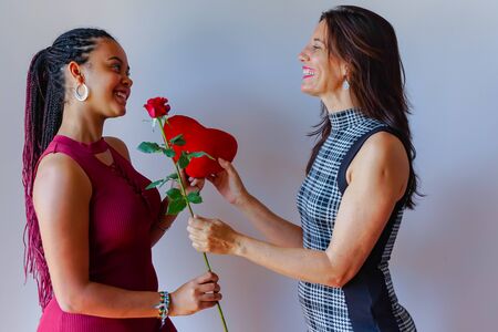 beautiful mother giving gift red rose and heart to her daughter indoors. love's celebration - Imageの写真素材