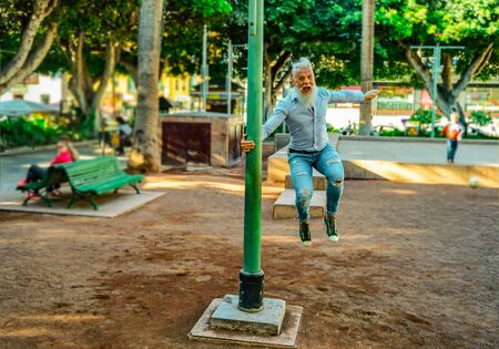 Smiling senior man relaxing in the park. Mature male having fun and jumps like a child. - Focus on this face - Imageの写真素材