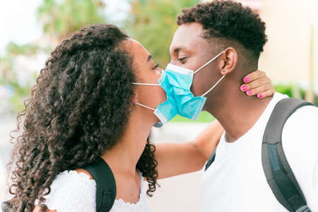 Young couple kissing while wearing face surgical mask during coronavirus outbreak. Relationship and Covid 19 concept.の写真素材