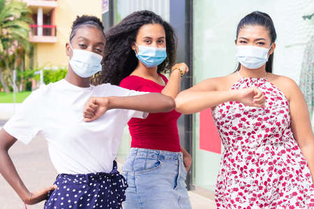 Young girls wearing face mask doing new social distancing greet with elbows for preventing corona virus spread. Covid 19 and friendship conceptの写真素材