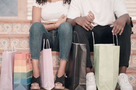 Midsection of couple with shopping bags. Closeup of woman and man on the colored stairs with colorful shopping bags. Holiday and buy concept.の写真素材