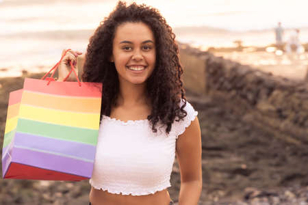 Young girl hold a rainbow bag. Concept of sexual minority and LGBT. Happy woman after of shopping...