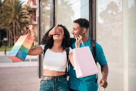 Beautiful young loving couple. The boy joking with girlfriend. Young couple with shopping bags near of mall. Love and shopping concept.の写真素材